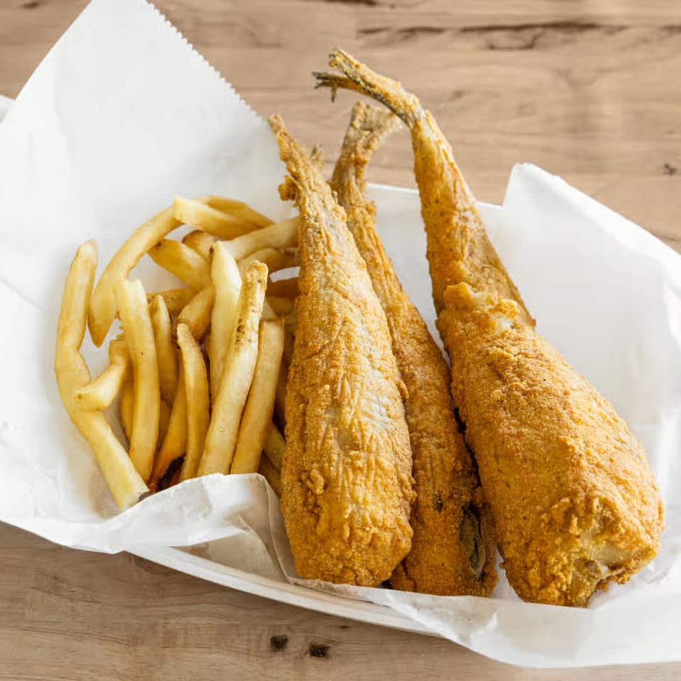 Three pieces of fried fish and a pile of french fries in a paper-lined basket.