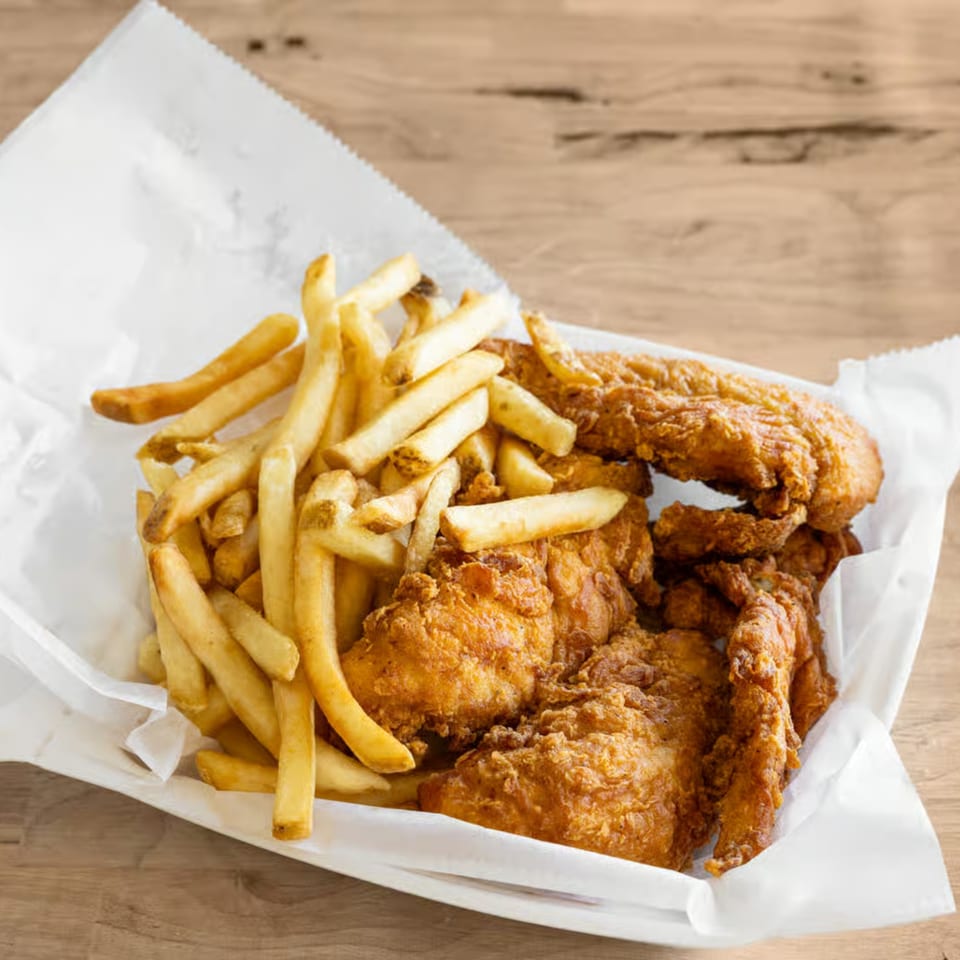 Golden-brown fried chicken and crispy french fries served in a white paper-lined basket.